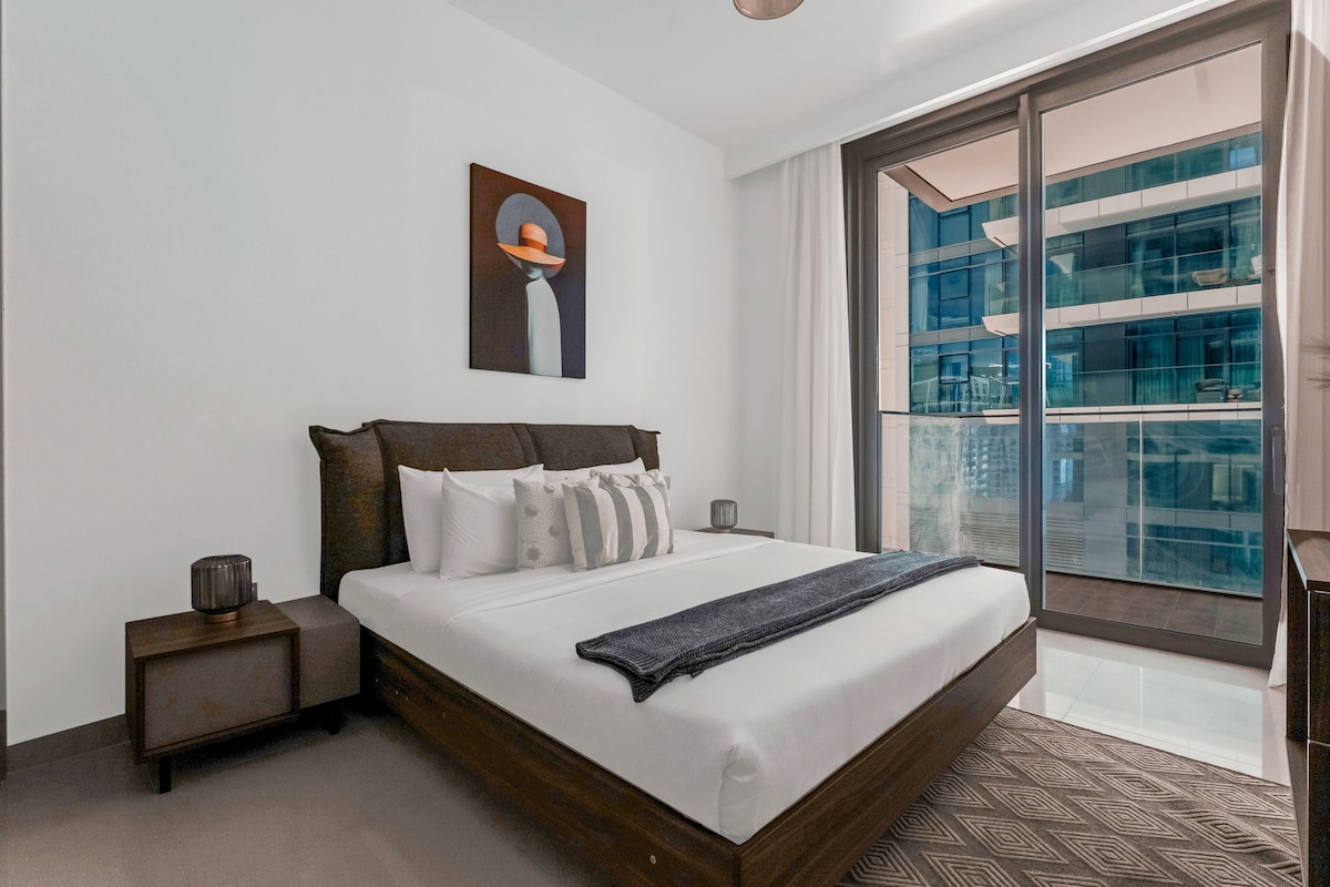 Chumba cha kulala cha Chic chenye ufikiaji wa roshani, mandhari ya jiji na kitanda cha kifahari.