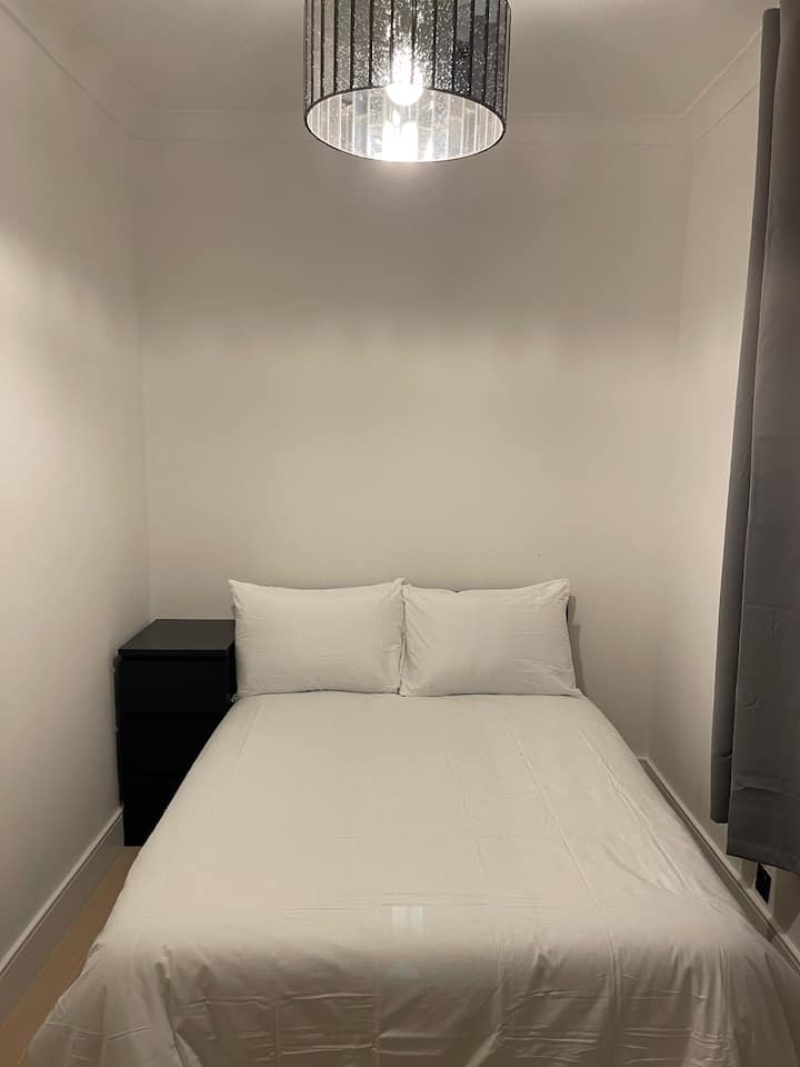 Ორადგილიანი საწოლი გვერდითი მაგიდით, ბუნებრივი განათებით, სათავსოებითა და ტანსაცმლის მოაჯირით