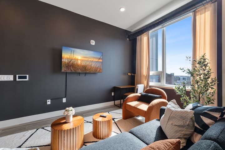 Moderne woonkamer met donkere accentmuren, stijlvolle bank en ronde salontafels. Deze vakantiewoning combineert modern design met gezellig comfort - gezinsvriendelijk Airbnb-verblijf perfect voor bijeenkomsten en ontspannende nachten.