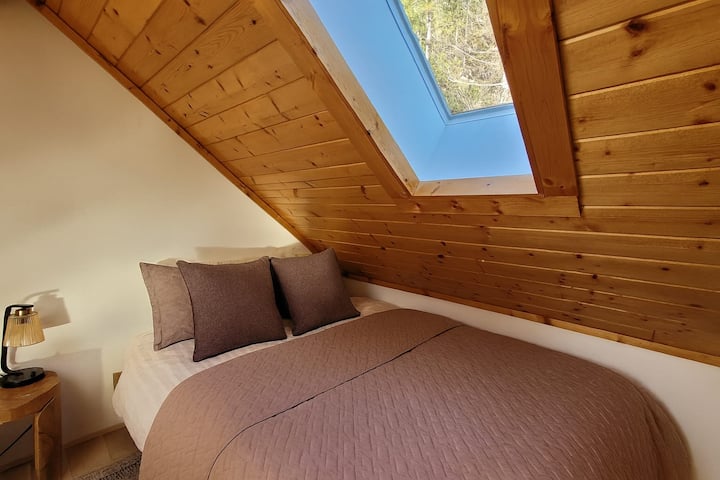 Queen bed in lofted bedroom, partially enclosed for privacy. Ladder access.