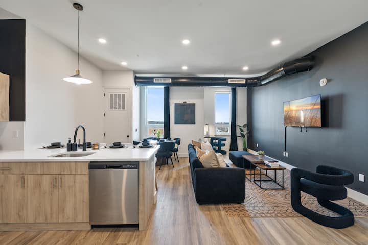 Dnevni boravak otvorenog tipa s mekanim kaučima, stolićem za kavu i prirodnim svjetlom koje ulazi u kuhinju. Smještaj za odmor s modernim dizajnom – savršen za obitelji i okupljanja, obroke i večeri uz filmove.