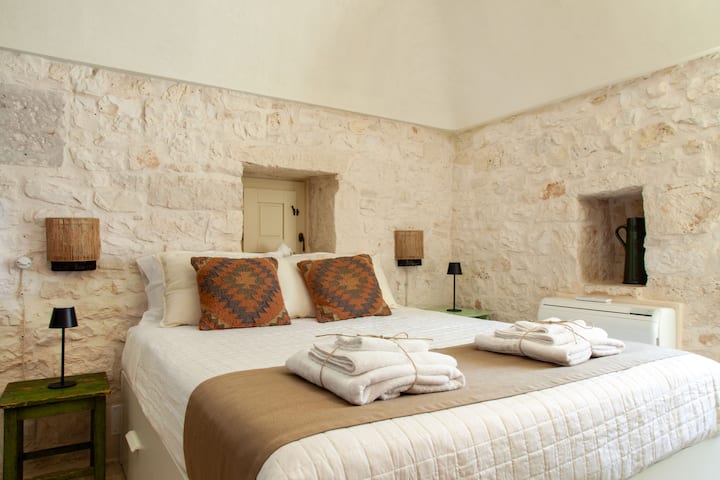 Camera da letto accogliente con pareti in pietra, che offre un'atmosfera rilassante, accesso diretto ai servizi esterni e bagno privato per il massimo comfort.