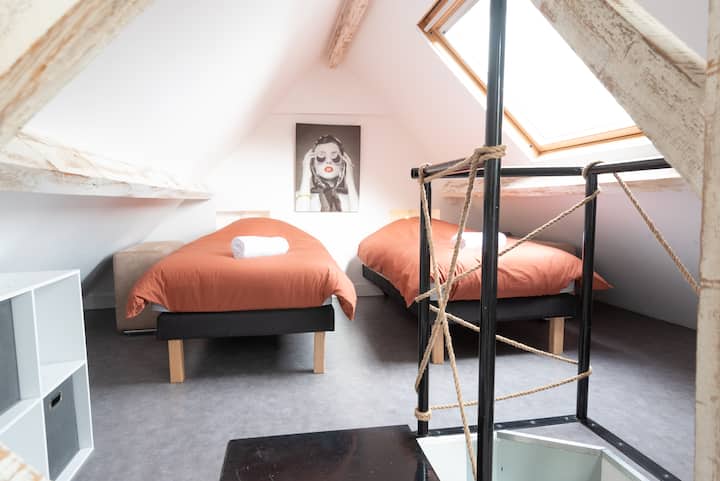 Habitación dúplex con dos camas individuales, lámparas de noche, cortinas opacas y zona de juegos