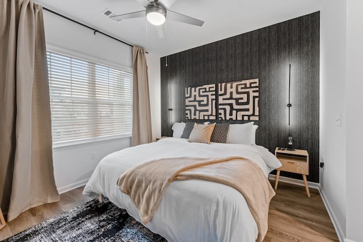 Модерна елеганција се среќава со удобноста – оваа стилска спална соба има брачен кревет, впечатлив темен акцент на ѕидот и меко осветлување за топла, привлечна атмосфера. Опуштете се во луксуз по долгиот ден и искористете ги завесите за затемнување!