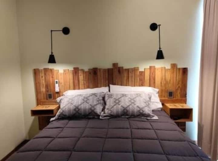 Habitación con cama Queen. La habitación tiene baño privado y salida a una terraza con vista a la montaña y parrilla individual