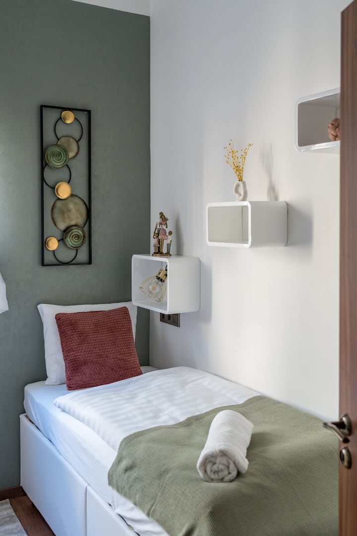 Chambre lumineuse sur le thème du printemps avec deux lits simples confortables. La chambre est climatisée et dispose de volets motorisés pour plus de confort. Un grand rangement et la climatisation offrent une atmosphère confortable et reposante.