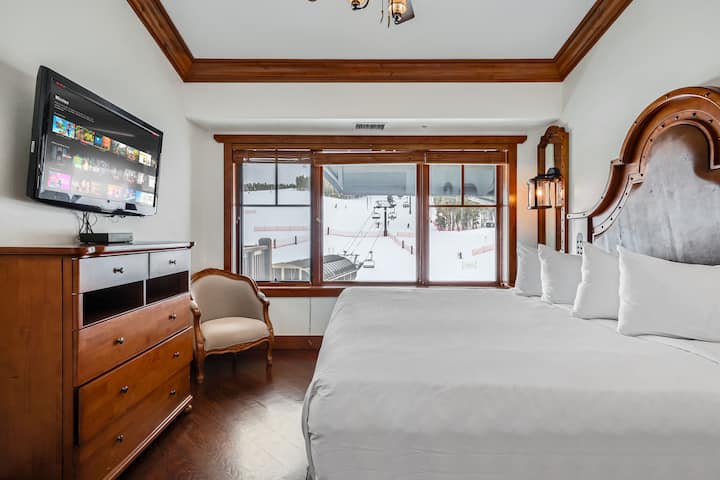 Chumba cha 1 cha kulala kina kitanda cha kifahari cha kifalme cha televisheni iliyowekwa ukutani kwa ajili ya burudani na madirisha makubwa ambayo yanaonyesha mandhari ya kupendeza ya milima na kuunda mazingira tulivu na yenye utulivu.