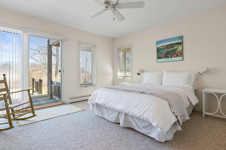 Mirna spavaća soba s bračnim krevetom s luksuznom hotelskom posteljinom i klizačem koji vodi do dvorišta za opuštajući odmor.