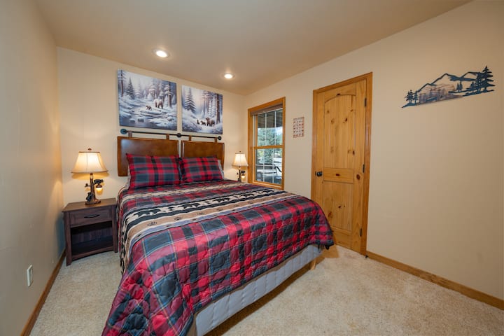 The smallest room in the cabin also features a Queen bed, with tasteful mountain decor, and a view of the front yard.