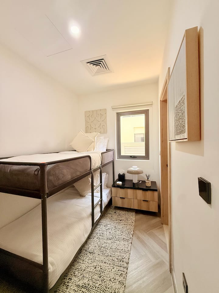 Спална соба 5/Собата на слугинката има удобни двокреветни кревети на спрат со удобна постелнина и голема ноќна масичка за дополнително складирање. Не е прикажан простран плакар лево, кој нуди простор за закачување и фиоки за дополнително складирање.