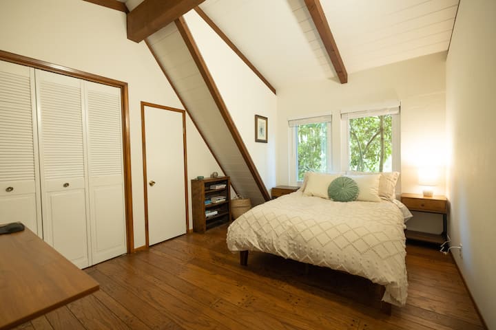 Los techos abovedados y las vigas expuestas enmarcan este dormitorio lleno de luz, donde los suelos de madera cálida y los tonos neutros suaves crean un escape sereno: aireado, acogedor y cuidadosamente discreto.