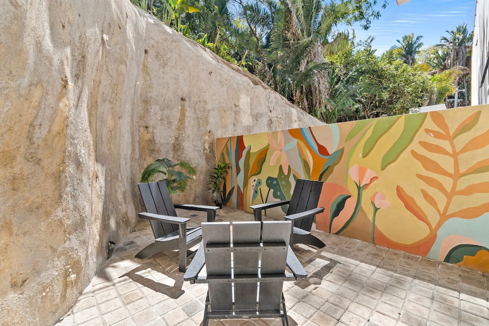 Private patio with chairs and a painted mural wall
