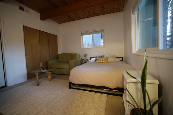 Ფართო მეორე საძინებელი თანამედროვე საწოლით, Crate and Barrel-ის კაბინის დივნით და ბუნებრივი განათებით, რომელიც ორი ფანჯრიდან ჩნდება