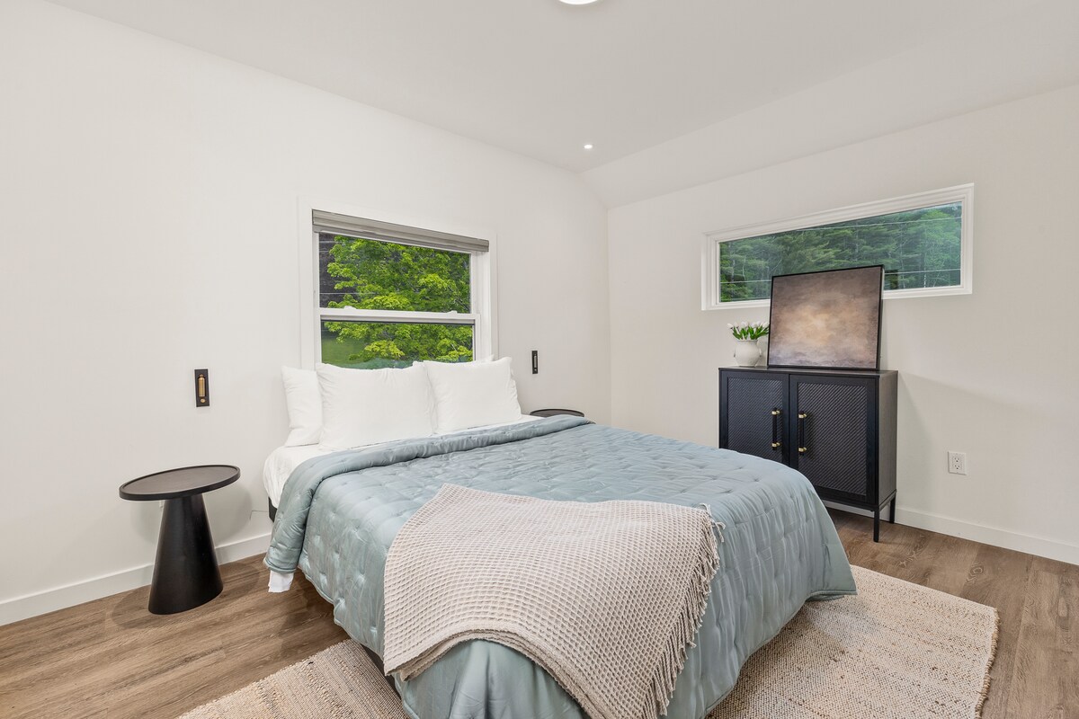 חדר שינה עם מיטת קווין סייז וחדר רחצה משותף במסדרון.