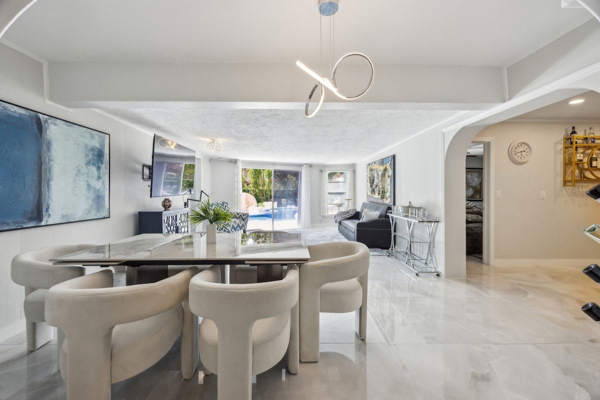 Elegant dining space with marble-style table and ultra-comfy chairs. Open layout flows beautifully into the living room with direct views of the pool and patio.