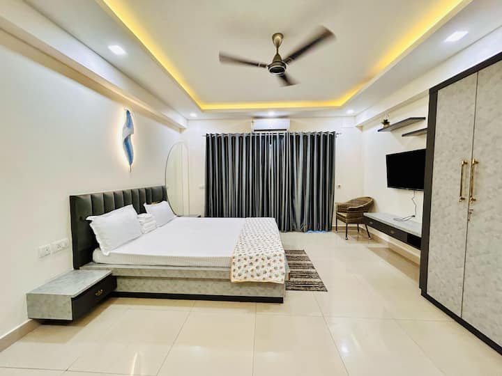 Vstúpte do krásne navrhnutej spálne, ktorá kombinuje pohodlie s eleganciou. Priestor je vybavený manželskou posteľou s jasnou posteľnou bielizňou so vzorom srdca, mäkkými vankúšmi a čerstvými bielymi plachtami – ideálne na pokojnú noc.