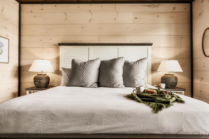 Kitanda cha kifahari chenye mito laini, blanketi la starehe na taa za kitanda zenye joto.