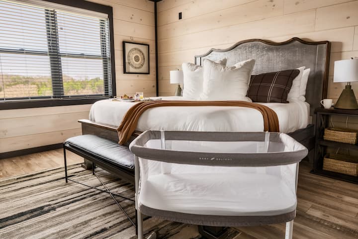 Kitanda cha kifahari chenye mito laini, madirisha makubwa, benchi na dari ya mbao yenye joto.