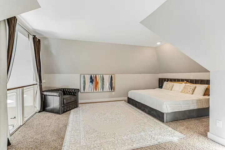 Prekrasna soba u potkrovlju s plišanim madracem i bračnim krevetom. Raspored sjedenja i prekrasni ukrasi.