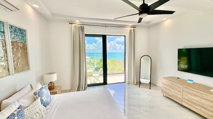 Chambre King avec vue sur l'océan, plafonds de 3,35 mètres et portes coulissantes avec moustiquaires s'ouvrant sur un balcon privé. Profitez de sièges en plein air et de vues à couper le souffle dans cette retraite spacieuse et aérée avec une vue imprenable sur l'océan et les levers de soleil.