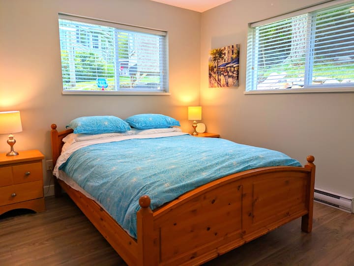 Ამ საძინებელში არის საწოლი Queen, რომელშიც არის ორი გვერდითი მაგიდა, ორი ლამპა და კარადა საკიდებით.