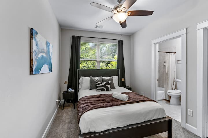 غرفة الضيوف في الطابق العلوي مع سرير بحجم متوسط وستائر تعتيم ومروحة سقف وتلفزيون ذكي.