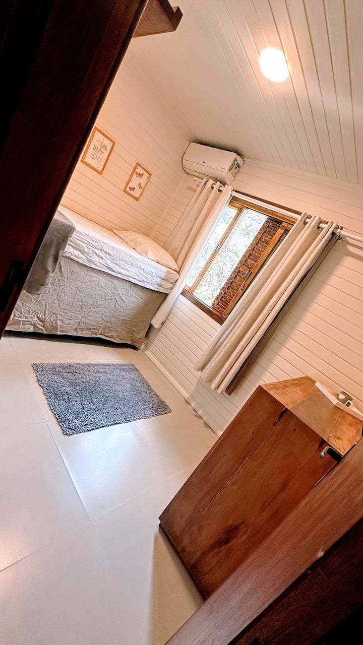 Quarto de solteiro com uma cama e mais um colchão disponível para colocar no piso.