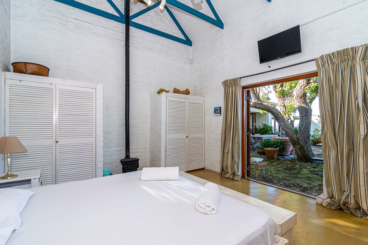 1 x King Size Bed. En-Suite Bathroom Smaller TV (wall mounted) View of enclosed garden & outside access to room. Overhead fan. Queen Anne Stove (Fire place).