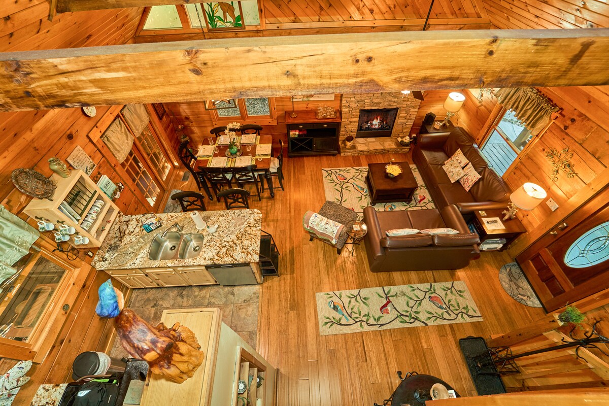 מבט מלמעלה על אזור המגורים מהלופט העליון הסגור חלקית מציג את האווירה החמה והביתית של הבקתה.