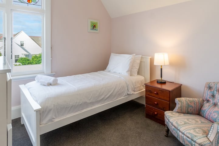 Udoban krevet za jednu osobu s hrskavom posteljinom i dekorativnom stolicom