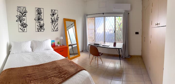 Grande chambre avec lumière naturelle, bureau confortable et fenêtre donnant sur le jardin, idéale pour se reposer