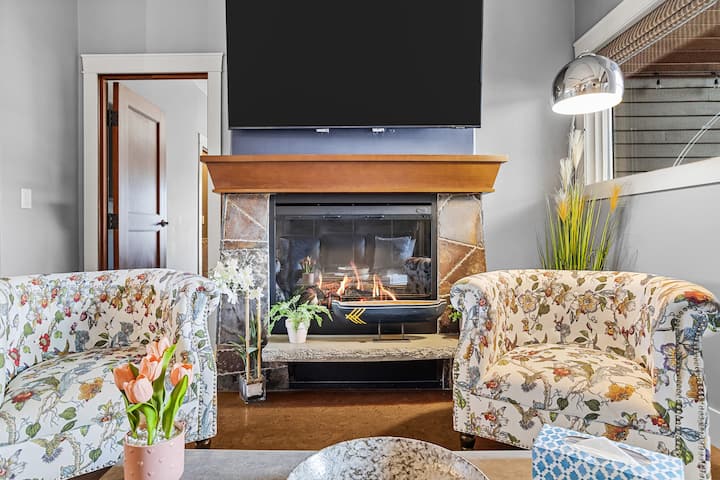 Elegante sala de estar con techos de 9,5 pies, una acogedora chimenea eléctrica, televisor inteligente y decoración elegante, perfecta para relajarse después de un día en las montañas.