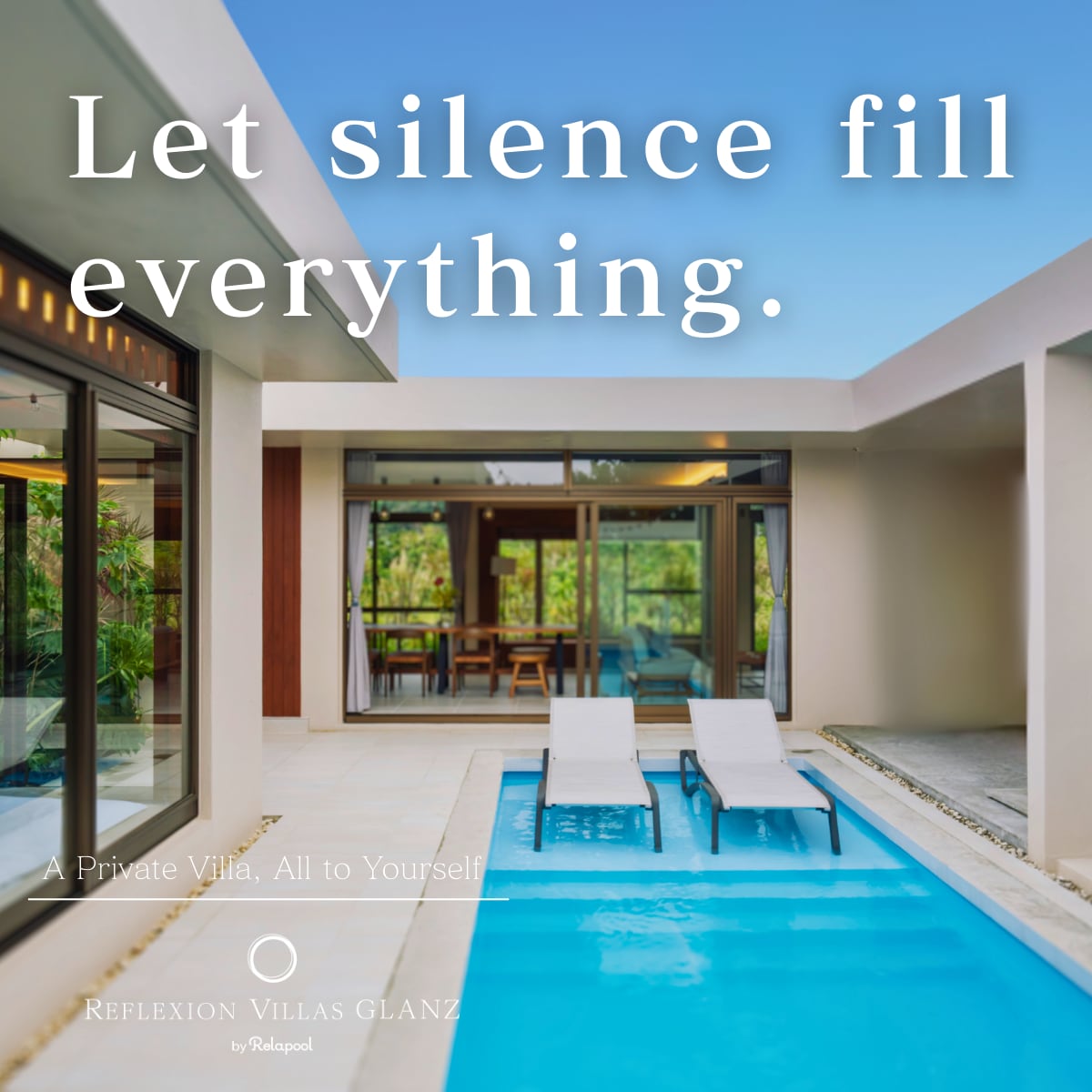 A tranquil private pool area is featured, flanked by two sun loungers. Large glass doors open to a spacious living area, inviting natural light and lush greenery from outside. The clean, modern lines of the architecture are complemented by a serene atmosphere.