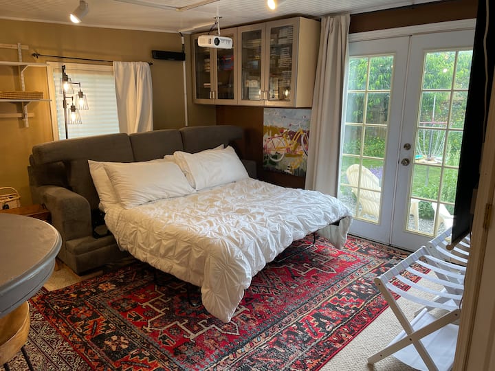 Sivá rozkladacia pohovka rozložená na posteľ. Matrac sivého rozkladacieho gauča (v diaľke) meria 170 cm na dĺžku a 152 cm na šírku.