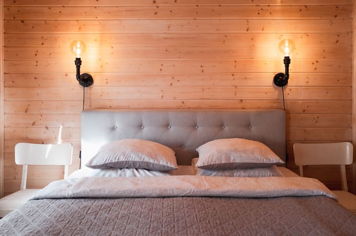 La cama principal con 2 lámparas de lectura y sillas vintage como mesitas de noche.