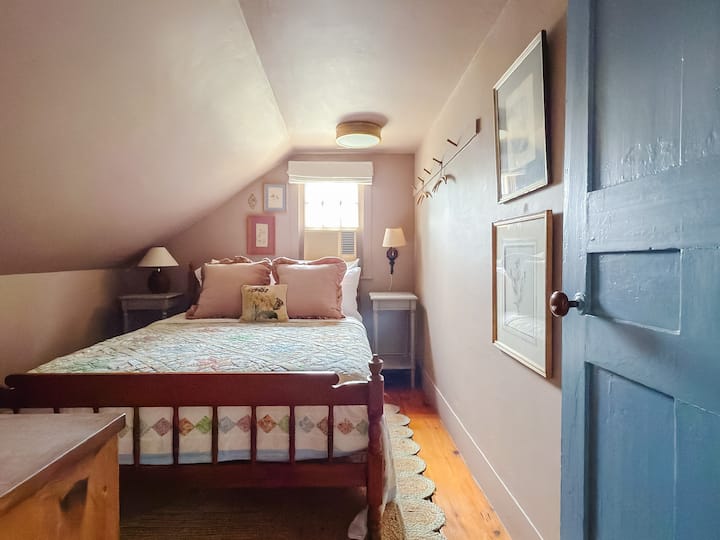 Full bedroom on second floor decorated in cottagecore style, with brand-new luxury mattress and high-end linens. Each bedside table has a reading lamp and charging port for convenient device charging. 