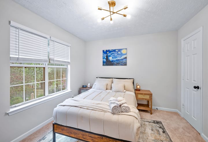 Ervaar ultiem comfort in deze uitnodigende slaapkamer, met een gezellig tweepersoonsbed en twee nachtkastjes die opslag en gemak bieden. De kamer is versierd met een prachtige canvas reproductie van Vincent Van Gogh's 'Sterrennacht'. 