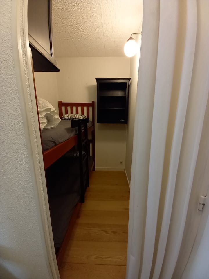 Dva kreveta u brvnari s dva mala ormara za odlaganje.