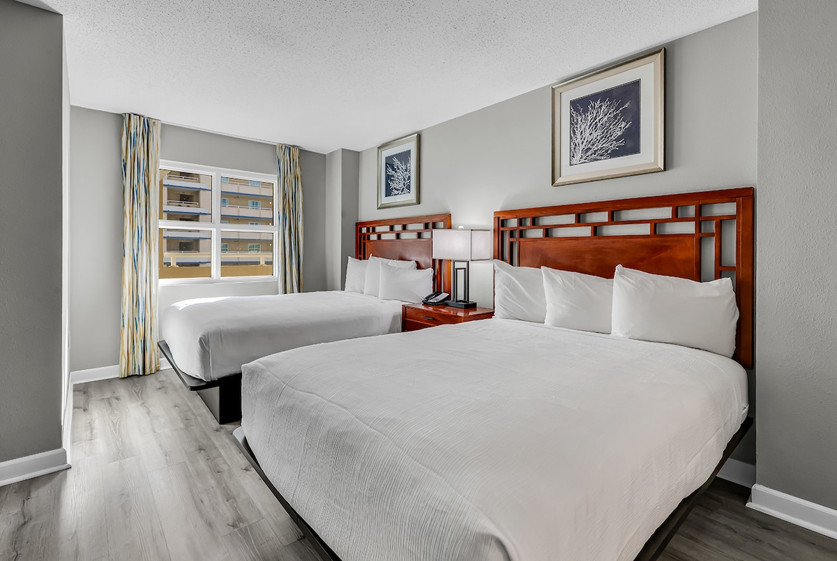 غرفة نوم واسعة وجذابة تتميز بسريرين مريحين وبياضات جديدة ونوافذ كبيرة تسمح للضوء الطبيعي بملء الغرفة.