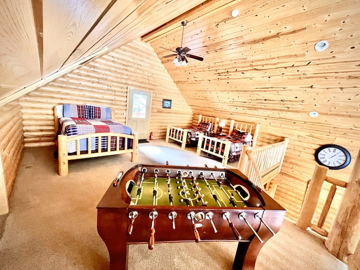 Chumba cha kulala cha roshani chenye nafasi kubwa kina kitanda cha watu wawili na vitanda viwili, vinavyofaa kwa familia au makundi. Furahia meza ya mpira wa magongo, pumzika kwenye roshani yenye mandhari ya mbao, au angalia eneo kuu la kuishi huku ukipumzika katika sehemu hii kubwa, yenye starehe.