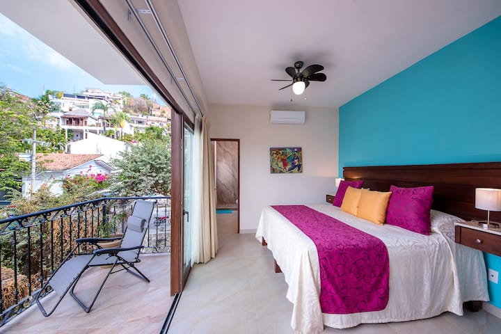 Acogedor dormitorio con cama tamaño king, armario grande, sillón cómodo, TV inteligente, aire acondicionado y ventilador de techo. Disfruta de tu café por la mañana en el balcón privado con asientos.
