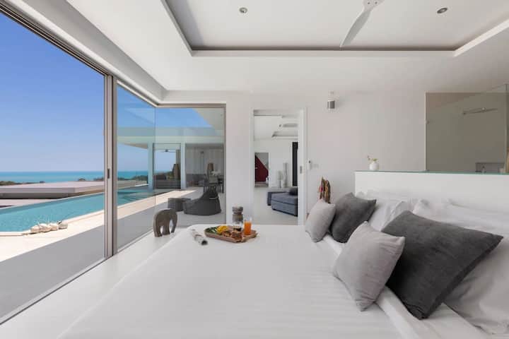 Despiértate con impresionantes vistas al mar desde este moderno dormitorio. Disfruta de una lujosa cama con suaves detalles grises y acceso directo a la piscina infinita. El diseño abierto se conecta a la perfección con la sala de estar, creando un refugio relajante y lujoso.