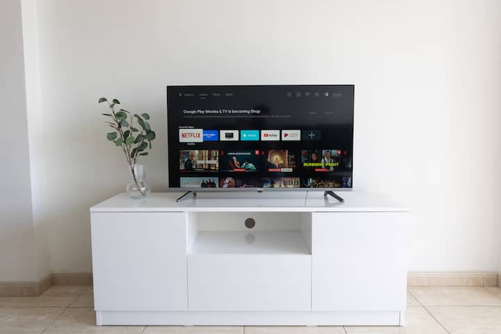 TV na stolu, s dekorativnom biljkom. Pogled s kauča.