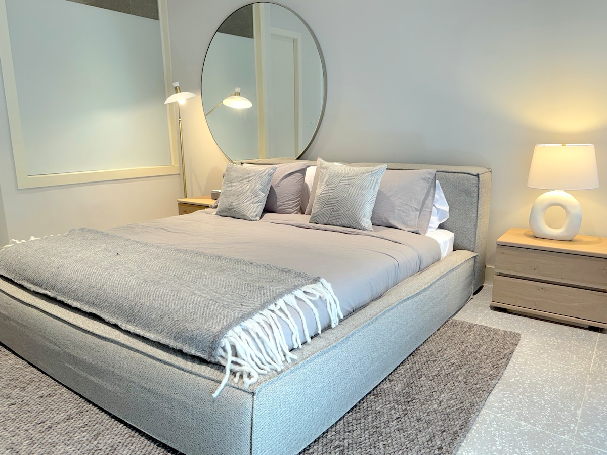 Détendez-vous dans le luxe dans cette superbe chambre principale, avec un lit king et des fenêtres en verre du sol au plafond pour laisser suffisamment de lumière naturelle dans la salle de bains attenante. 