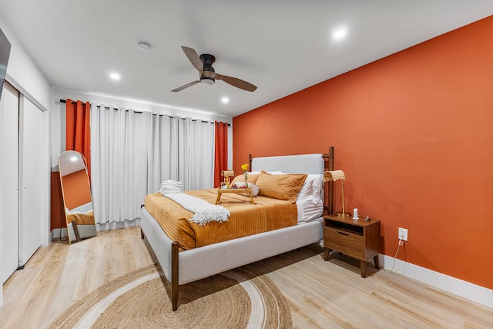 Recharge in this modern bedroom with bold terracotta walls, a plush bed, and a cozy seating area – perfect for a relaxing retreat.