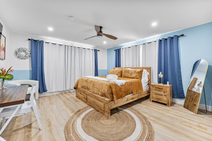 Unwind in this cozy bedroom featuring a plush king-size bed with warm golden tones, natural wood furnishings, and calming blue accents – the perfect retreat for a peaceful night's rest.
