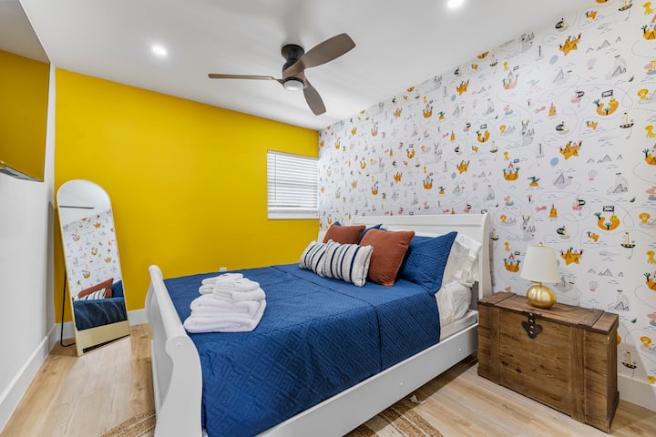  Brighten your stay in this playful bedroom, featuring bold yellow accents, nautical-themed wallpaper, and a cozy, inviting bed – perfect for a relaxing escape