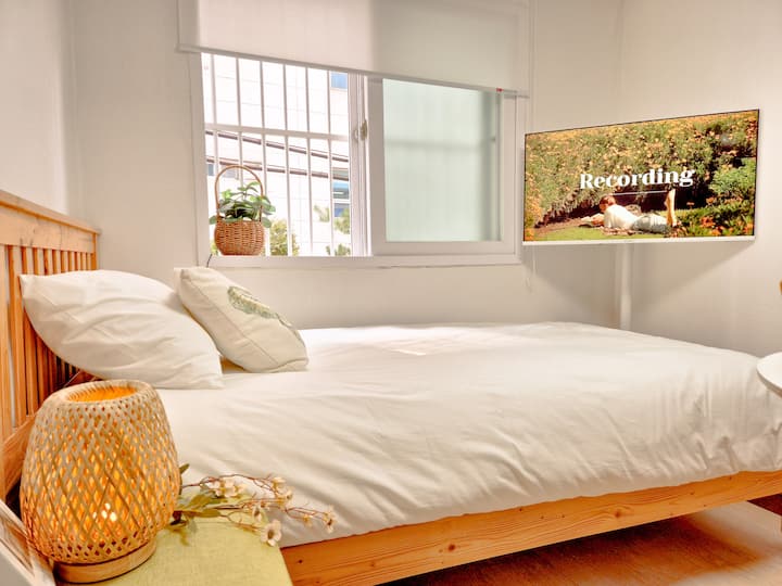 ห้องนอนที่มีการผสมผสานระหว่างเครื่องนอนสีขาวและกรอบไม้เพื่อเพิ่มความเป็นกันเอง

อบอุ่นและโปร่งโล่งด้วยแสงธรรมชาติที่ส่องเข้ามาทางหน้าต่าง

อารมณ์ธรรมชาติด้วยแสงหวายอารมณ์และอุปกรณ์ทางพฤกษศาสตร์

คุณสามารถดู Netflix และ YouTube ได้อย่างสะดวกสบายขณะนอนลง