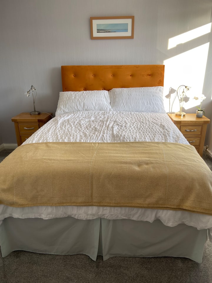  A charming good sized room with double bed, bedside units, table lamps, fitted wardrobe, mirror and chair, a fan.  The lower window has a window restrictor with quick release . Zipped bed/ pillow protectors. Quality linens, pillows, throw.