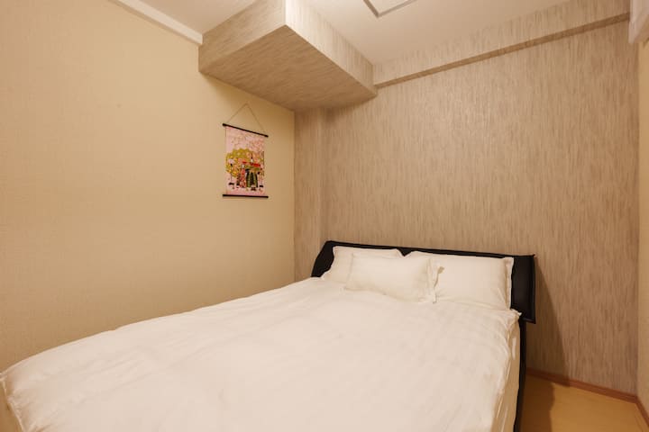 El dormitorio 3 tiene una cama tamaño queen de aproximadamente 1,5 metros con colchón suave y moderado, adecuado para un solo descanso grande o doble cómodamente.La ropa de cama es blanca, limpia y ordenada, y se limpia y reemplaza antes de la llegada.La habitación tiene una pared de color claro con una pared de fondo texturizada para un ambiente cálido y relajante.Hay una pintura japonesa colgante en la parte superior de la cama, que agrega un carácter de toque y viento a la habitación.Hay espacio activo alrededor de la cama, adecuado para viajeros de corta duración.No hay presión en la esquina y el área para dormir es tranquila y privada, lo que contribuye a una buena experiencia de descanso.